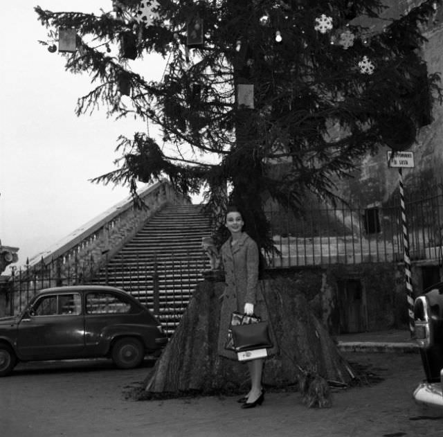 #85 Audrey Hepburn standing in front of a huge Christmas tree while visiting Rome over the holidays, 1950.