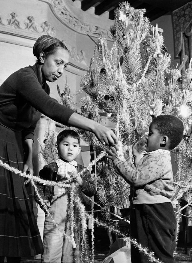 #88 Josephine Baker trims her tree with her children in her French chateau, 1956.