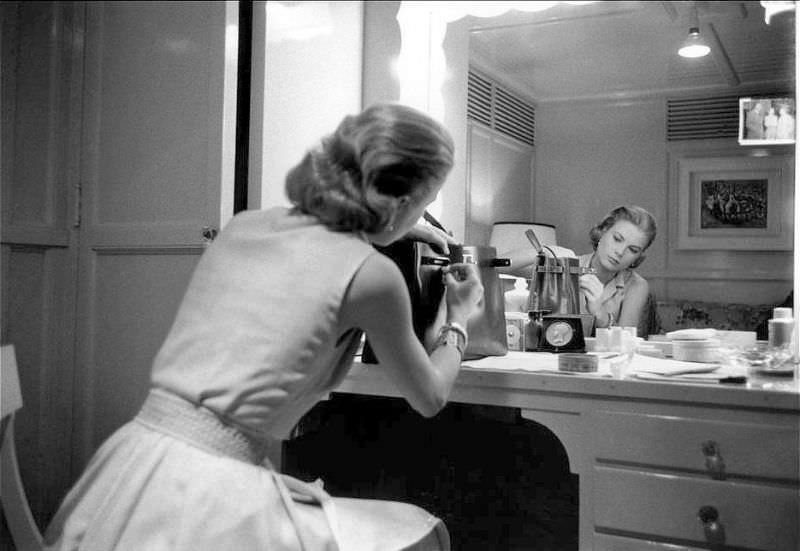 #26 Grace Kelly in her dressing room adjusts her handbag by Hermès named for her (the Kelly bag), 1956