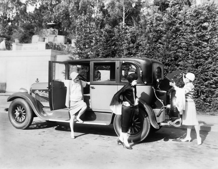A Studebaker automobile pictured with a trio of beautiful woman including one seen loading her luggage into the trunk compartment. Photographed in San Francisco’s St. Francis Wood neighborhood, circa 1926