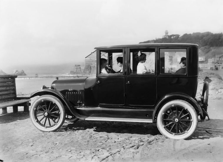 #9 San Francisco’s historic Cliff House and Seal Rocks as from beach level. An automobile loaded with a pair of ladies and two children pictured in the foreground, 1910s