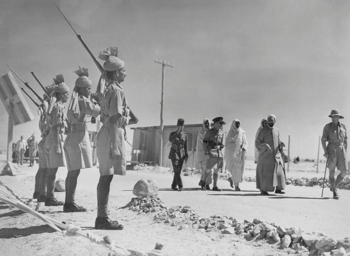 #26 Sayyid Muhammad Idris (1889 – 1983), leader of the Free Libyans, accompanied by Senussi, British and Egyptian officers and an Indian Guard of Honour during his exile in Egypt, 1940.