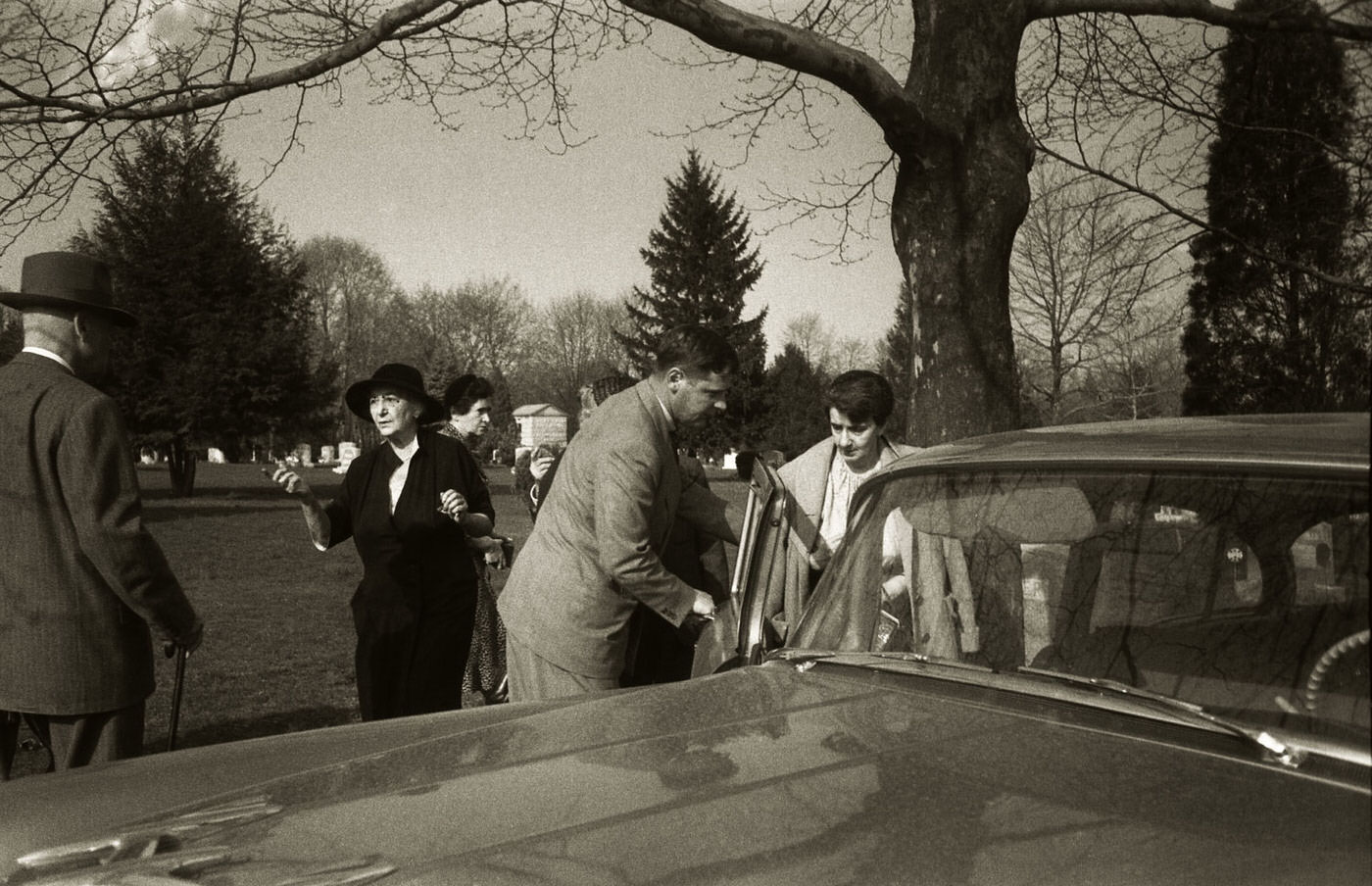 #7 After the cremation service, an unidentified man holds a car door open for Albert Einstein’s secretary, Helen Dukas, as she leaves the premises in April 1955.