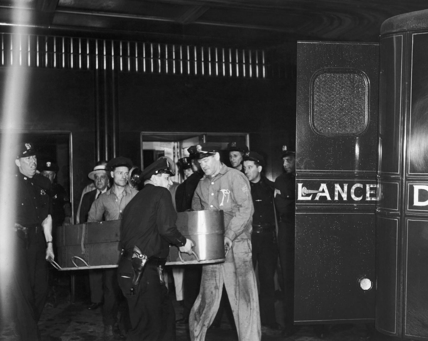 #13 The coffin of a crash victim is carried out of the Empire State Building to an ambulance on 34th Street, 1945