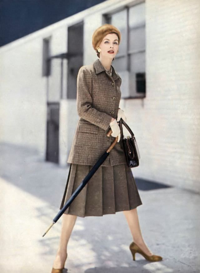 #28 Georgia Hamilton in amber tweed suit with jacket that can be a coat, with pale-amber crêpe blouse, by Handmacher, beret by Emme, Gucci umbrella, Koret bag, Vogue, September 1, 1955