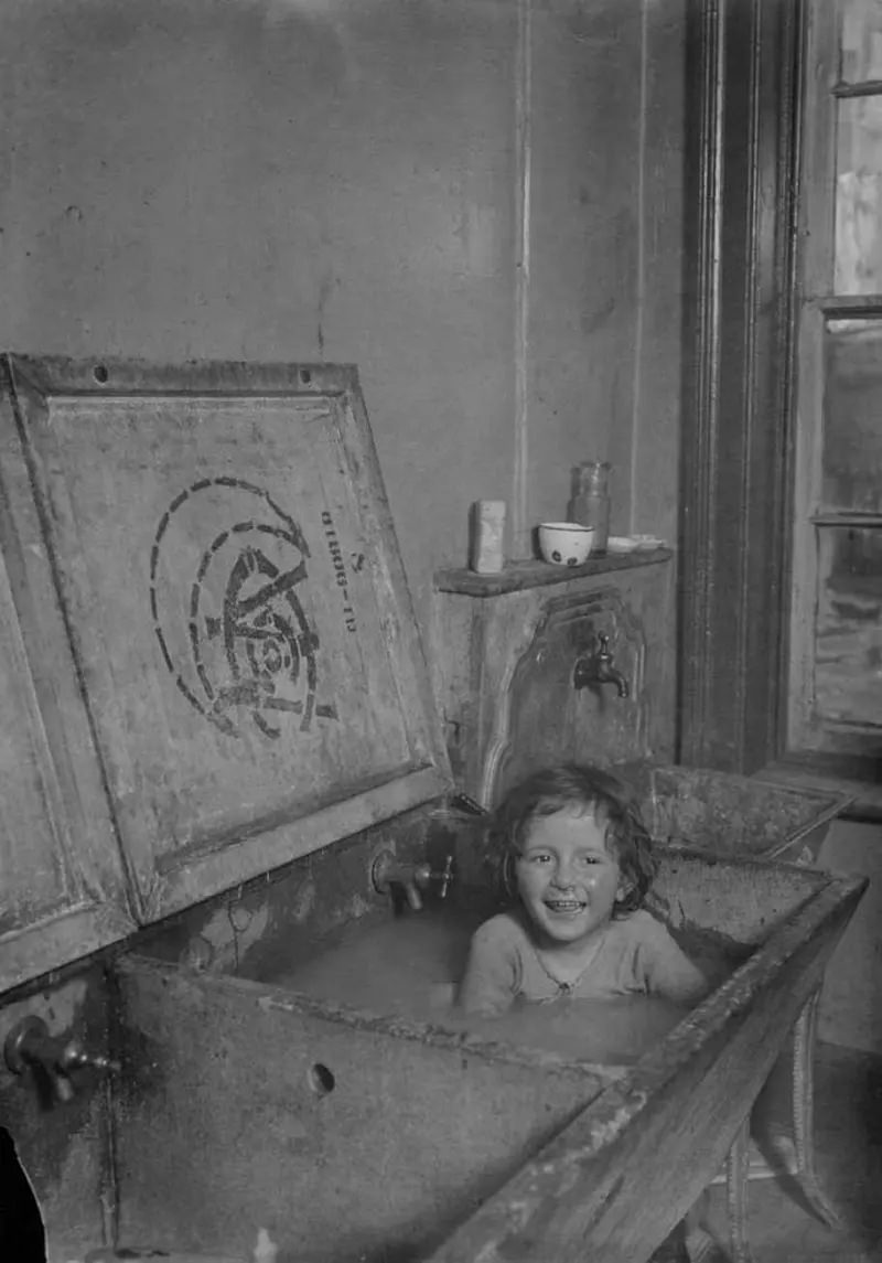 #35 A happy note in the old tenement life. Child is bathed and underwear is laundered at one time.