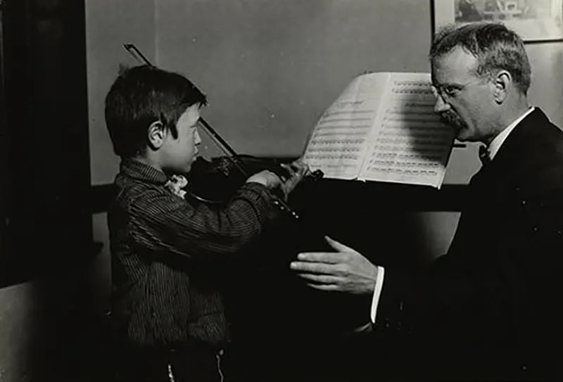 #36 A young refugee with musical talent receives instruction in Hull House music studio, 1910.