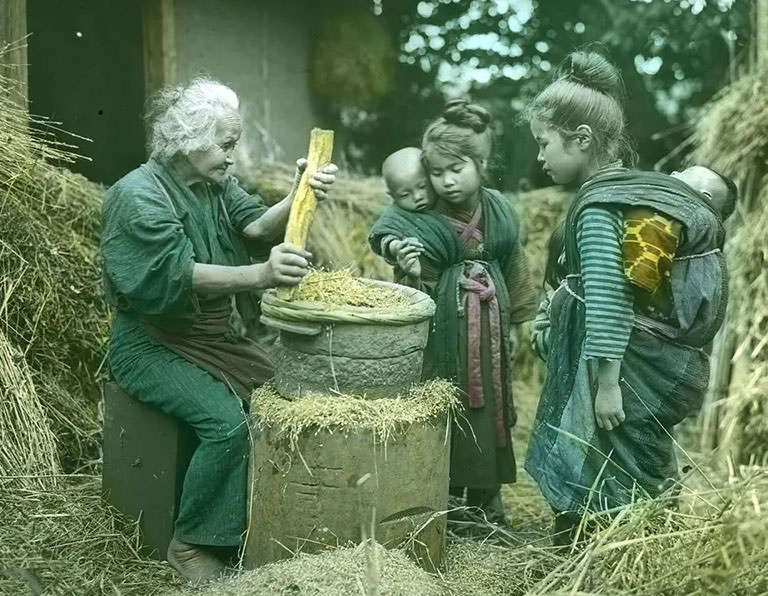 #17 Old woman with raised grinding stone; two little girls carrying babies on their backs looking on.