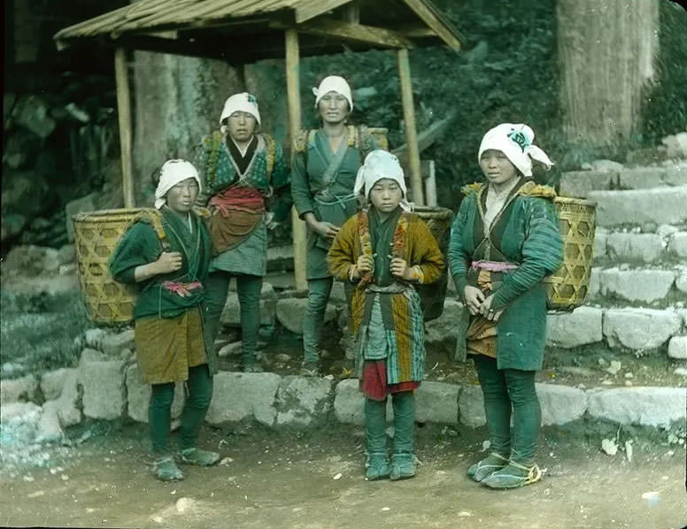 #25 Rural women in local attire carrying large baskets on their backs.