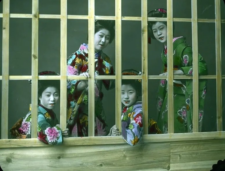 #41 Four women smiling and leaning through openings in lattice work.