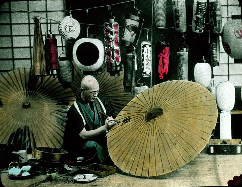 #9 Man painting parasols; painted lanterns in background.