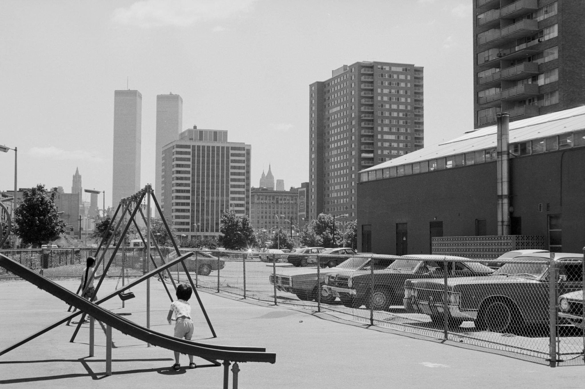#5 With the World Trade Center in the distance, view looking east at two children at play in a playground in a housing complex in downtown Jersey City, New Jersey, 1974.