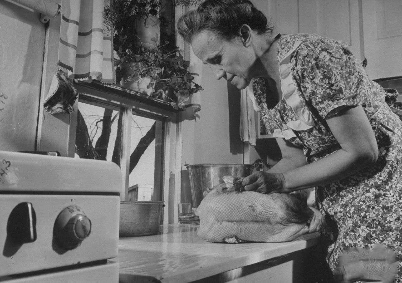 #12 Mrs. James Ferdinand Irwin in kitchen preparing stuffed goose for Christmas dinner that marks the first family reunion in years w. her sons safely returned from WWII.