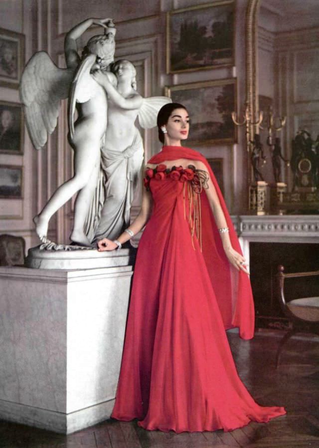 #16 Jacky Mazel in fiery red chiffon gown, a row of roses borders the draped bodice, by Grès, jewelry by Boucheron, Paris, 1956