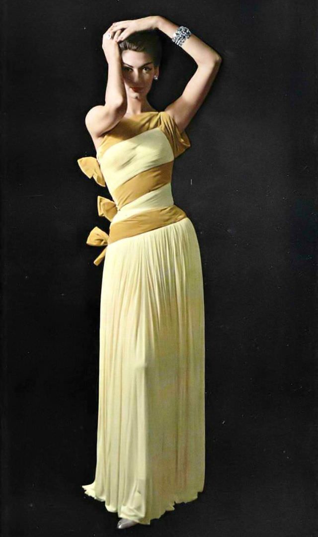#27 Simone d’Aillencourt in fluid one-shoulder mousseline jersey gown banded and tied in bows of velvet by Grès, jewelry by Scémama, 1957