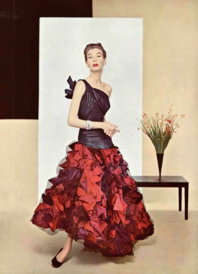 #8 Model in evening gown of extraordinary work in taffeta, the elongated bodice has one shoulder knotted in back, skirt is made of shells in several tones covered with fine net of black tulle by Grès, 1952