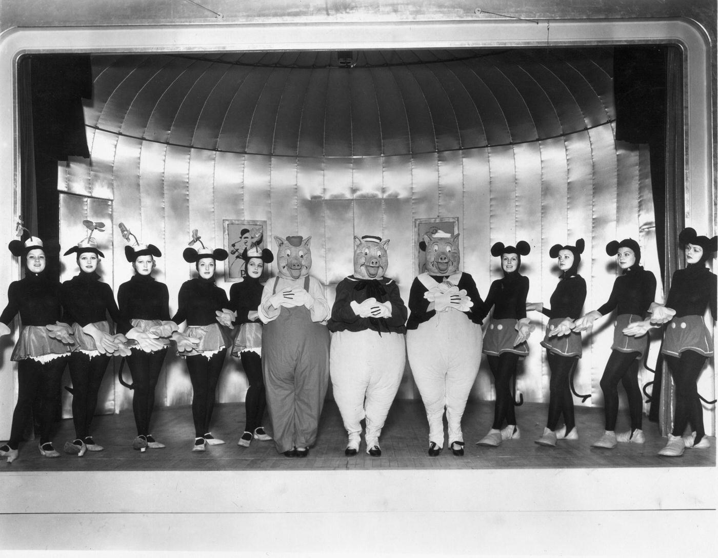 A cast of young women as Mickey and Minnie Mouse, and the Three Little Pigs in a production of ‘Monte Carlo Follies’ at the Grosvenor House Hotel, London, 1934.
