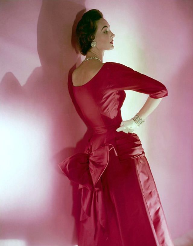 #11 Evelyn Tripp in a red silk twill dress with a bustle-bow by Mollie Parnis, rhinestone jewellery by Bogoff, Vogue, November 15, 1953