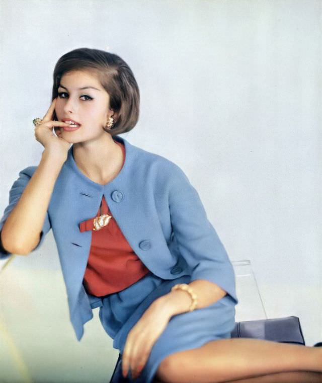 #26 Tamara Nyman in sky-blue wool tweed suit with geranium-pink silk blouse by Mollie Parnis, jewelry by David Webb, January 1, 1961