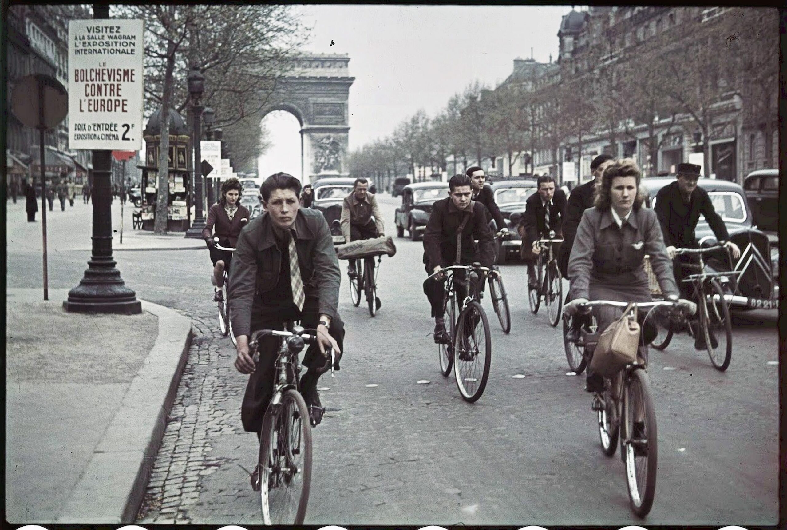 #19 Parisians cycle past a poster for Nazi-sponsored Europe Against Bolshevism exhibition.