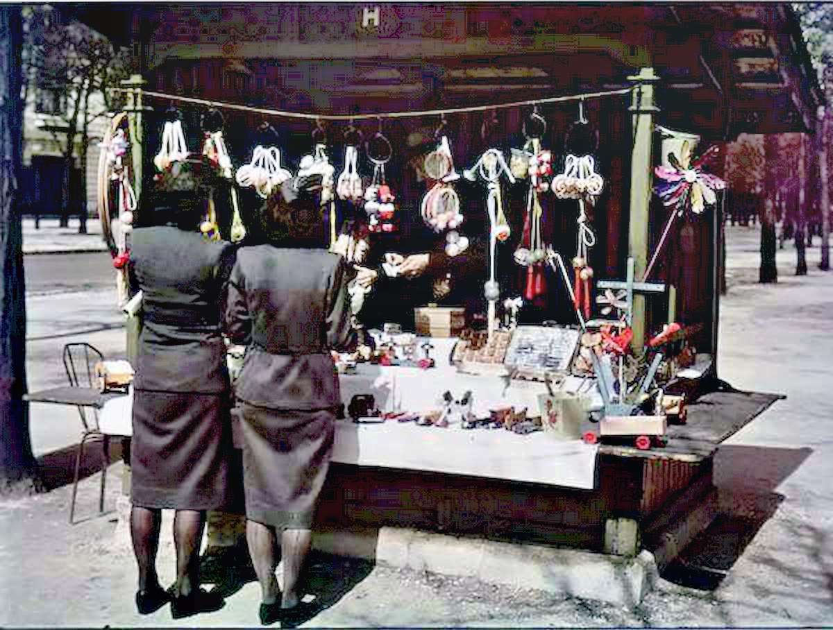 #3 Two women in military-style uniforms shop at a stall selling toys.