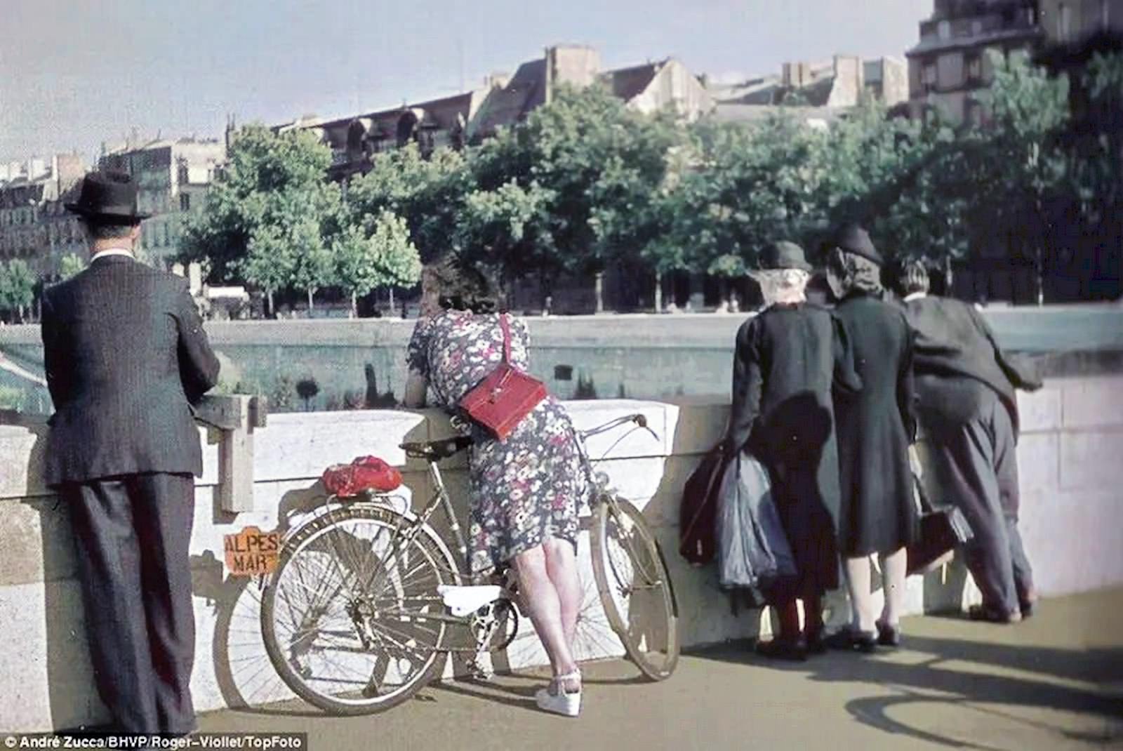 #50 A shapely woman leaning over the side of the bridge is the focus of this photograph.
