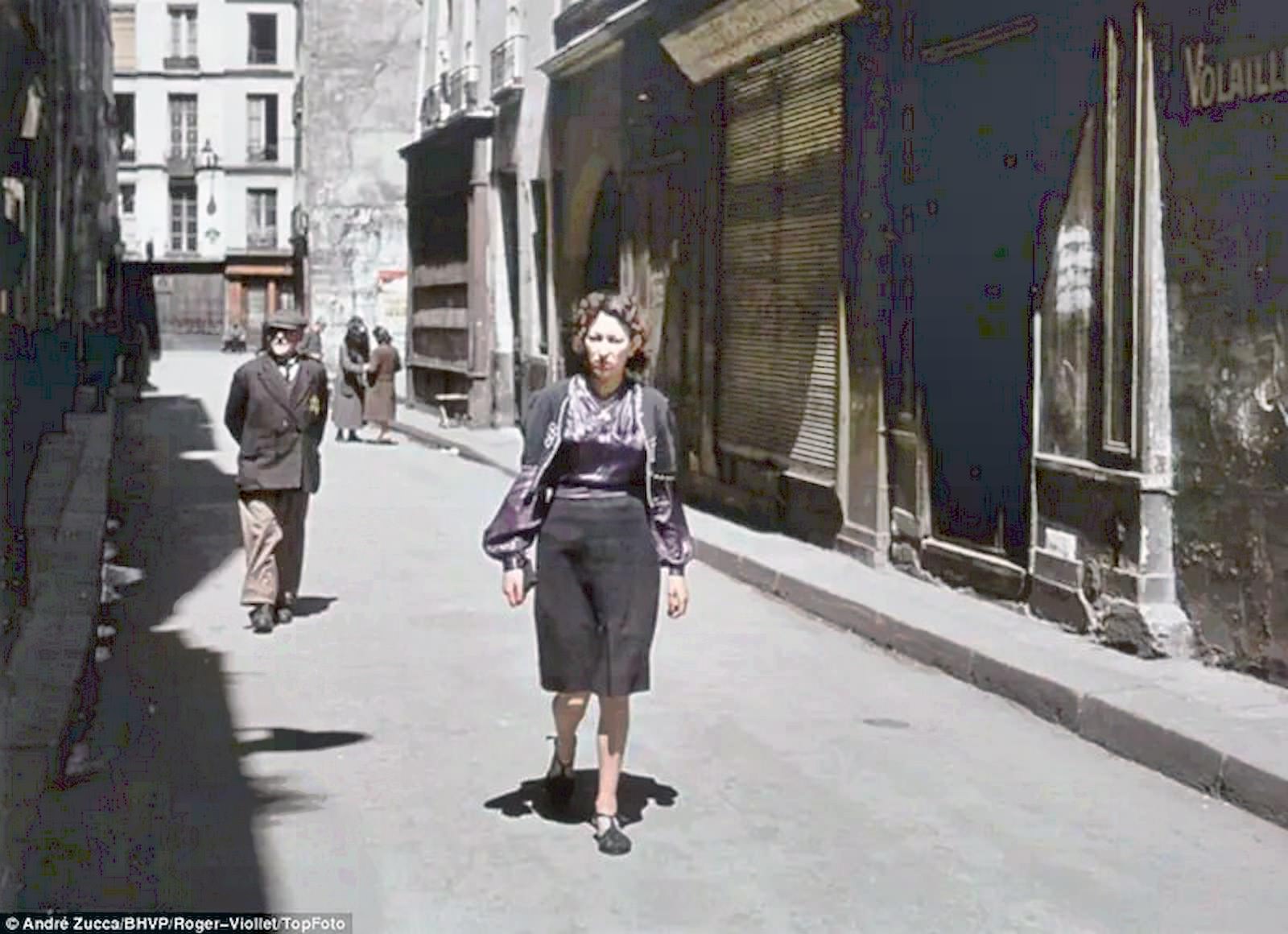 #56 A woman walks a Parisian backstreet, in front of an older gentleman who is marked with the Star of David insignia that Jews were forced to wear.