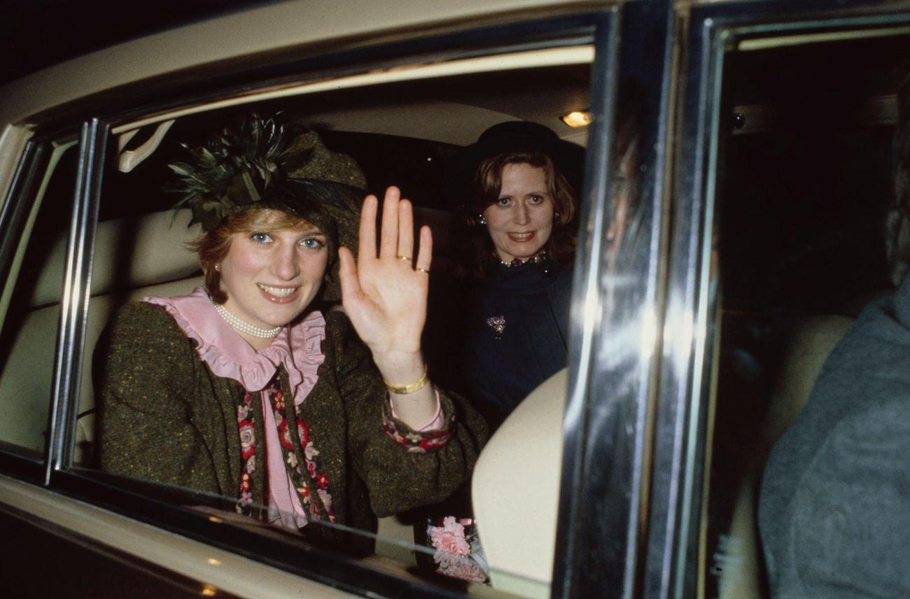 #48 Princess Diana with her lady-in-waiting Lavinia Baring waves from the back seat of a car during her visit to her hometown in Northampton, England, 1981.
