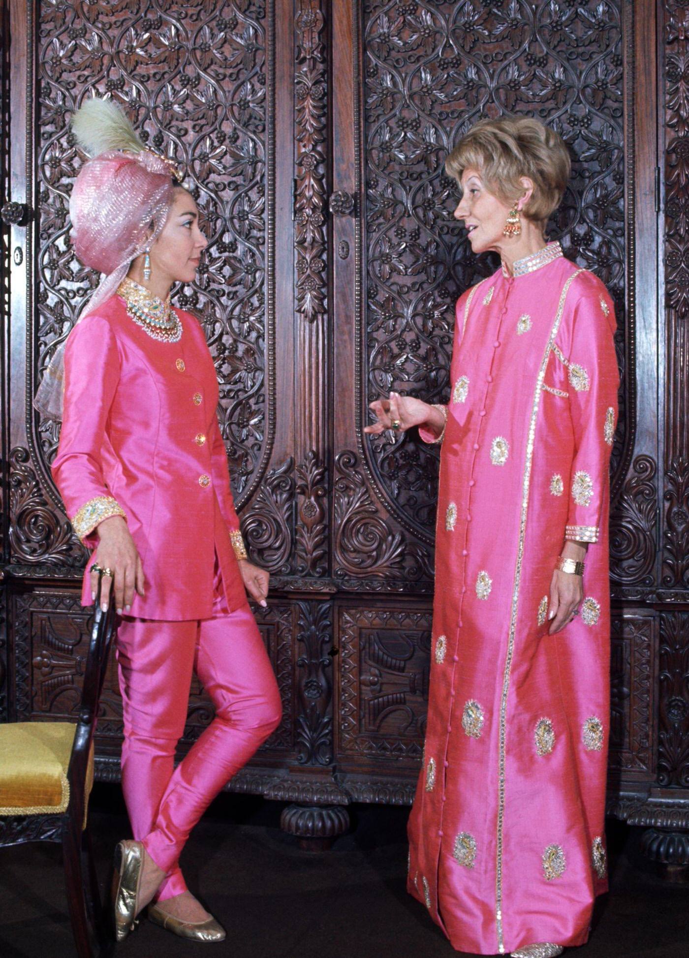 #1 Two women in a hippie fashion boutique, one wears a two piece trouser suit in pink silk with a pink turban head dress and gold ballet shoes, the other wears a full length pink silk Kaftan with gold embroidery, London, 1966