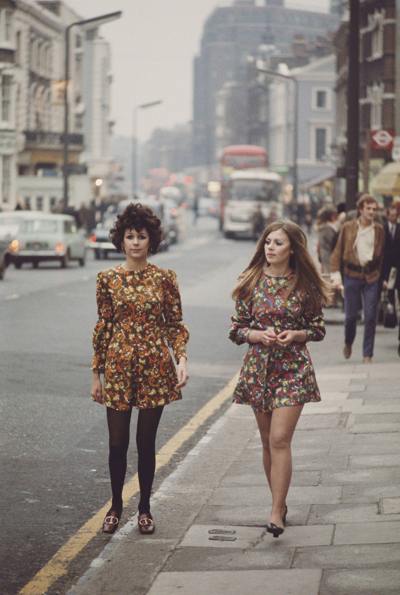 #8 Two young girls dressed in long sleeved floral print mini dresses walk along the Kings Road in Chelsea, London in November 1967.