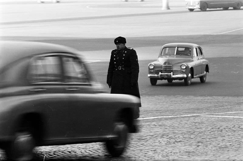 #54 A traffic policeman in the center of a wide cobbled avenue.