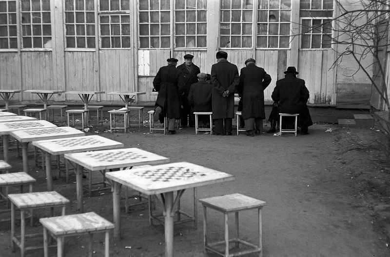 #56 Men playing chess in a courtyard.
