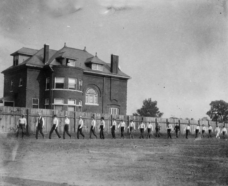 #246 Several unidentified men in line along fence, 1900