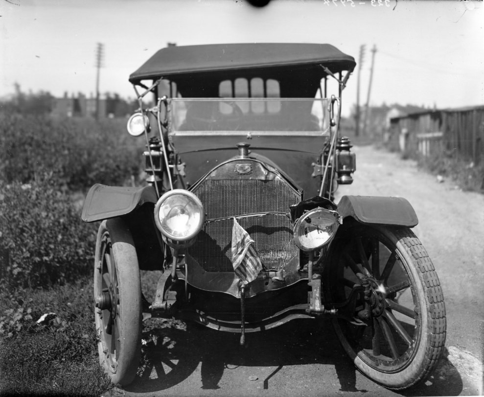 #66 Dorris automobile that has been in a wreck, 1900. An American flag has been tied between the headlamps
