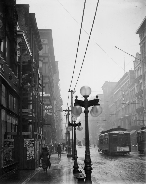#25 Rainy city street with street lamps visible in the foreground, 1900