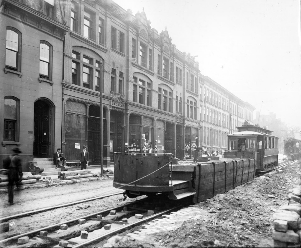 #56 Streetcars on street under repair, a modified streetcar with the cab removed is in the foreground, 1900