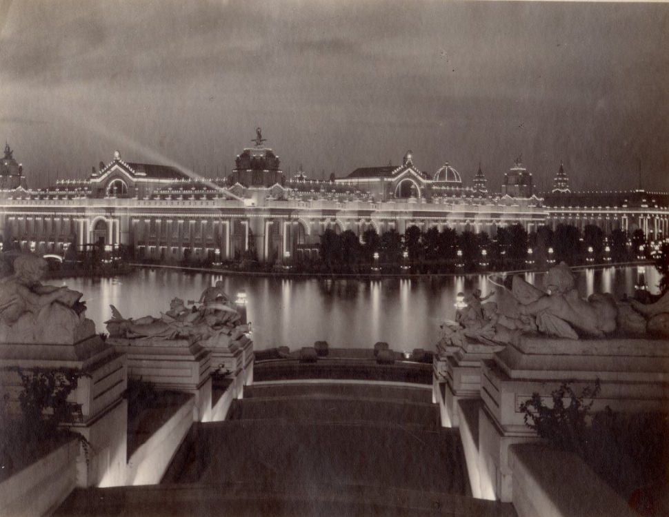 #77 Palaces of Electricity and Machinery, 1900. The image is of the buildings at night viewed from Art Hill looking across the Grand Basin.