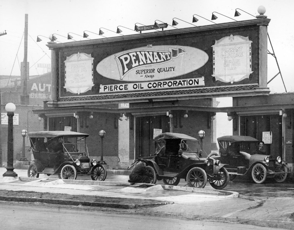 #78 Pennant Pierce Oil Corporation filling station, 1900. Three cars are visible in front. A man appears to be putting air into the tire of one of the cars.