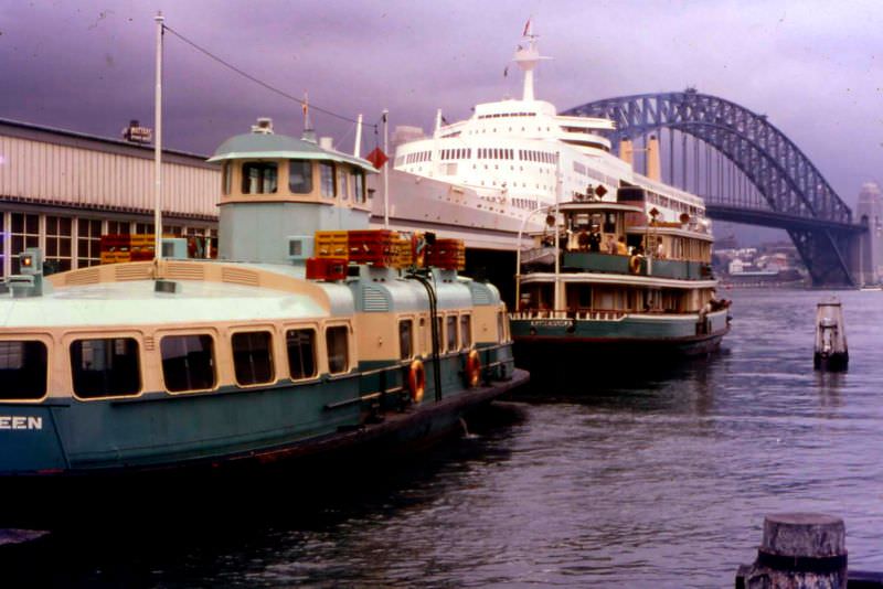 #49 The harbour ferries Kooleen and Kameruka in the foreground with an unknown ocean liner, probably the P&O Canberra, and the harbour bridge behind, Circular Quay, Sydney, 1969