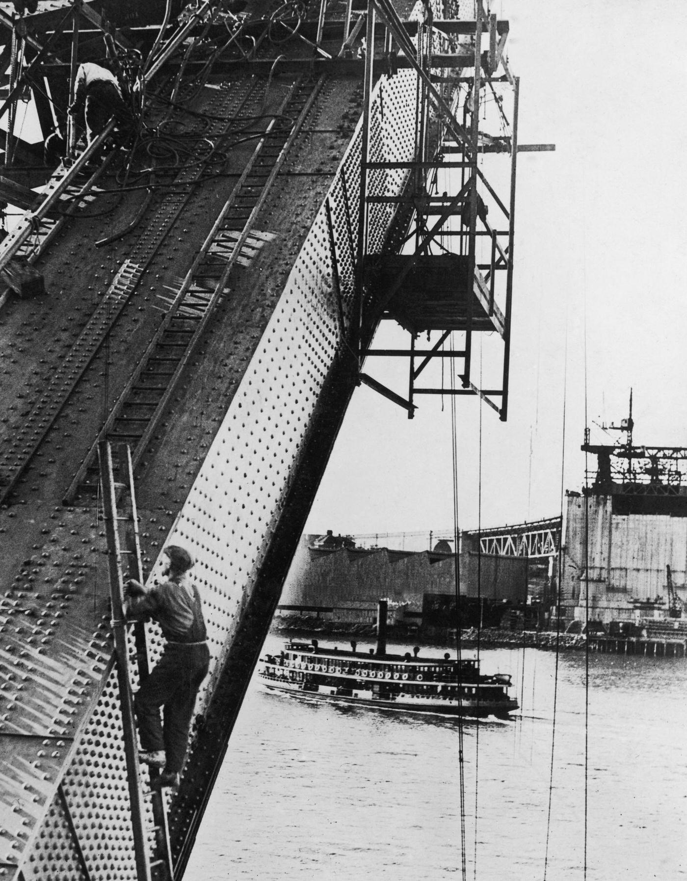 #42 A passenger steamer passes under Sydney Harbour Bridge during the construction of its arch, 1930.