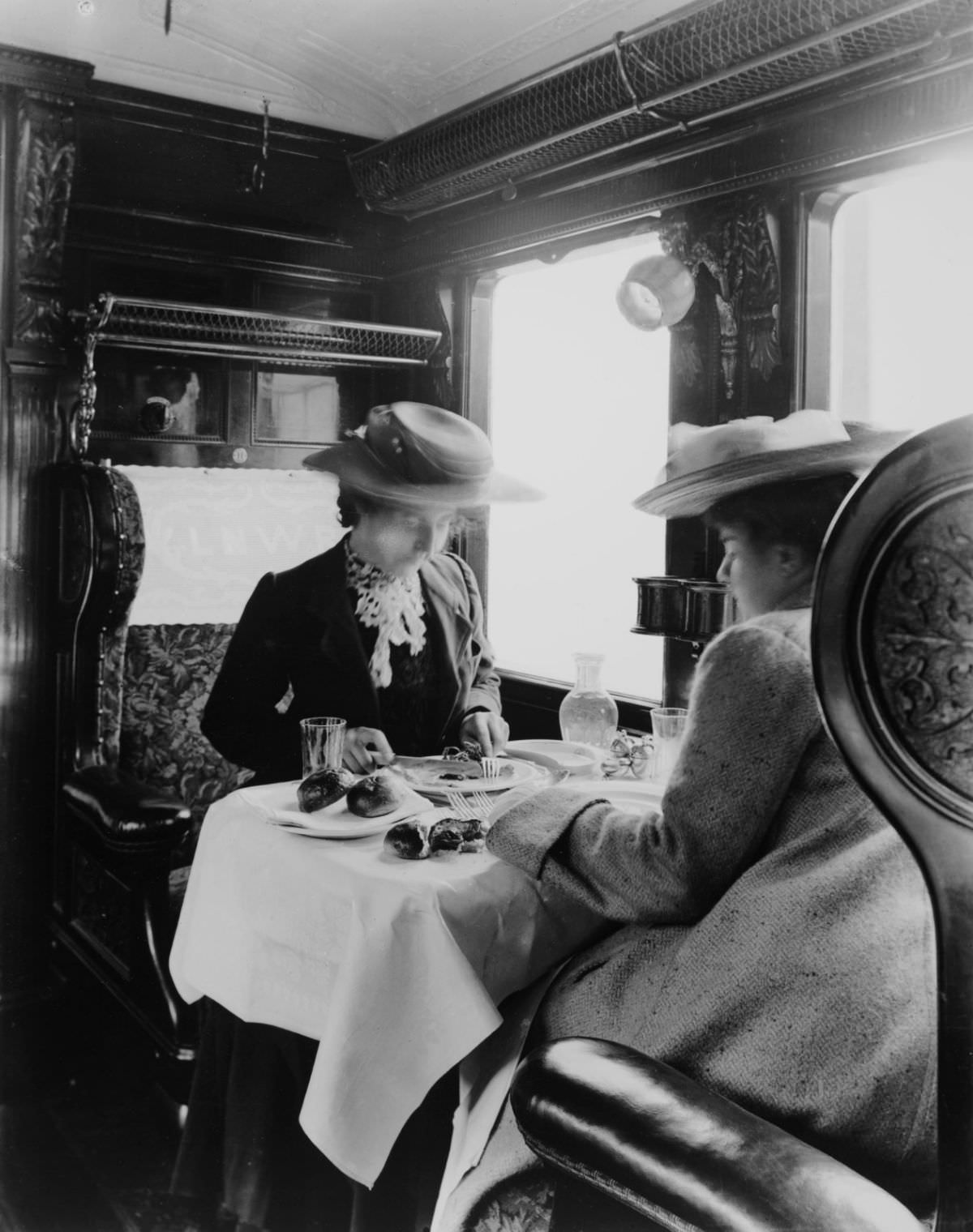 Two female passengers eating a meal in a London &; North Western Railway dining car, 1905.
