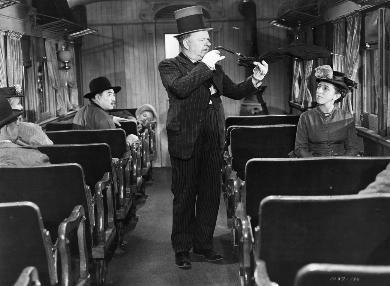 Margaret Hamilton bent umbrella in a scene from the film ‘My Little Chickadee’, in train
