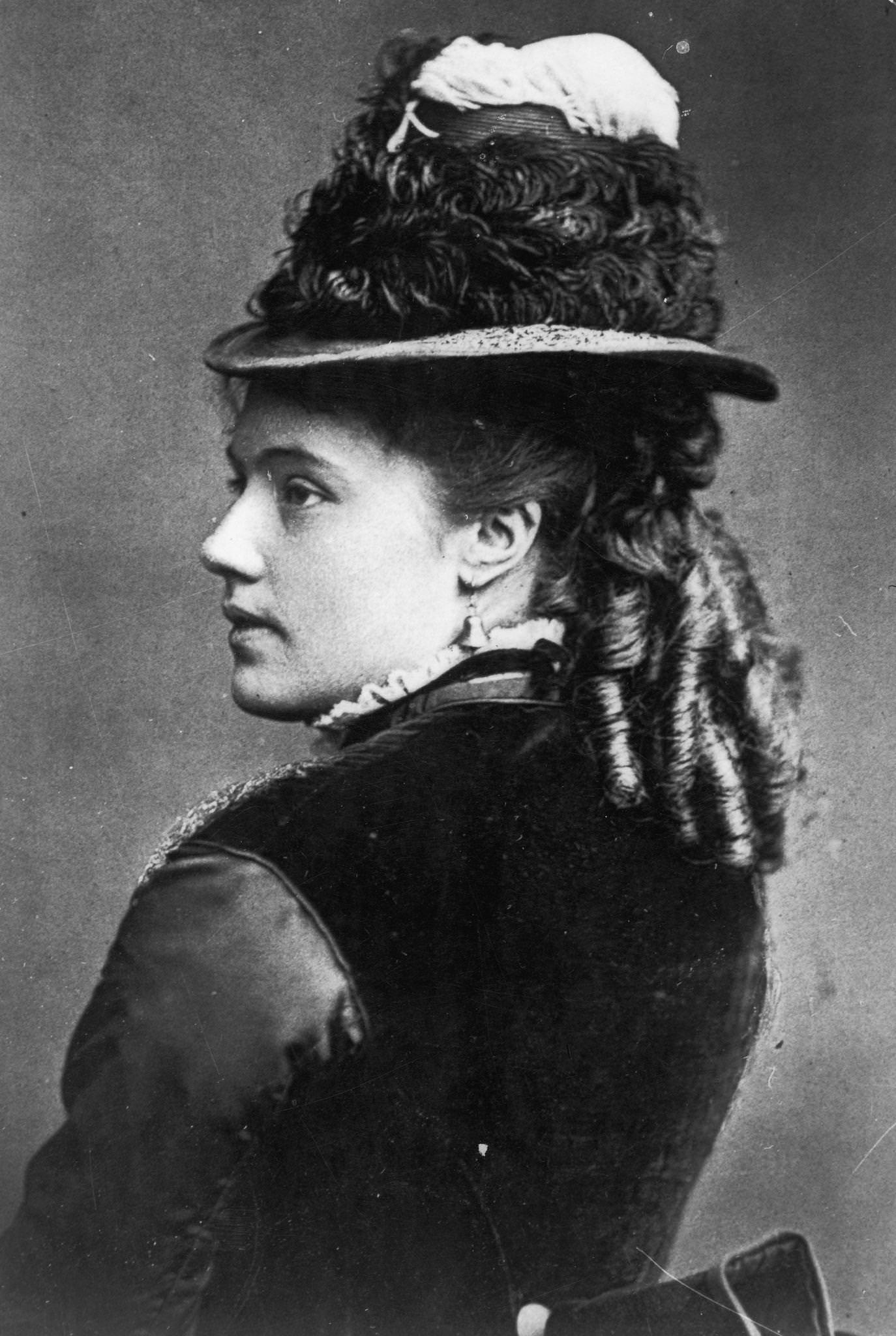#20 A young woman with her hair in ringlets and wearing bell-shaped earrings and a hat, 1855.