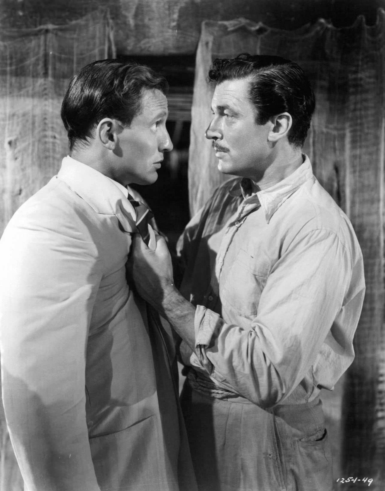 Walter Pidgeon being grab by his jacket by a man staring him in the eyes in a scene from the film ‘White Cargo’, 1942.