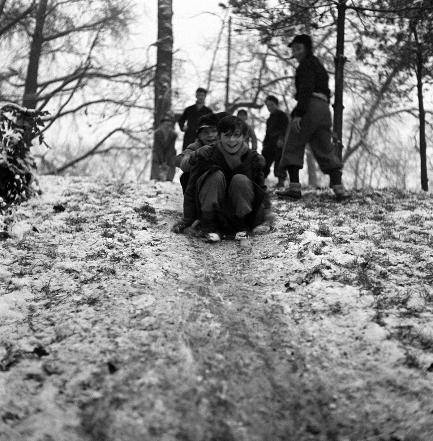 #50 Children playing on a slope covered with snow in a park after a snowfall. Milan, 1950s.