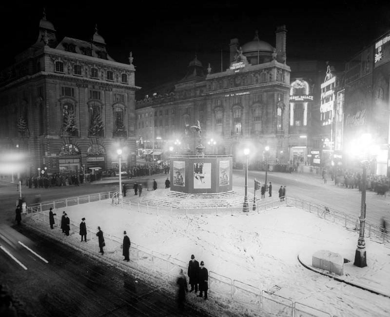 #25 The statue of Eros in Piccadilly Circus, London on New Year’s day, surrounded by policemen as midnight strikes, 1962. (Arthur Sidey)