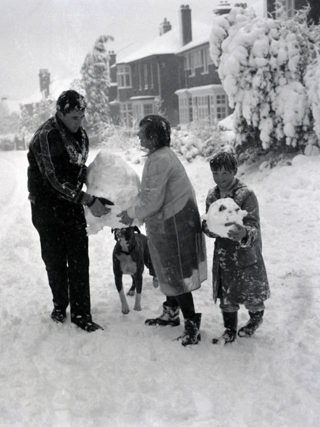 #27 Children build a snowman with the help of their boxer dog in Hadley Wood, Hertfordshire, 1962. (George Greenwell)