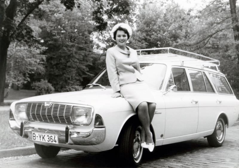 A brunette lady posing on the fender of a Ford Taunus 20M Turnier in a cobbled street. The print is dated “14.6.1966” on the reverse side. The car is equipped with a roof rack and registered in West Berlin, June 14, 1966