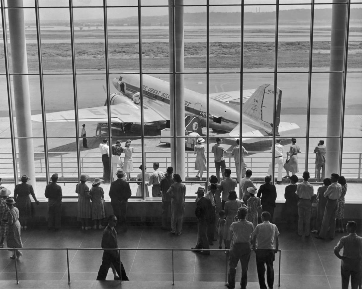 In 1945, a viewing gallery at an airport shows a Douglas DC-3 airliner of Eastern Airlines (‘The Great Silver Fleet’).