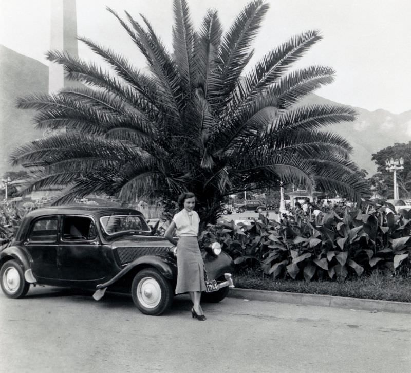 Lady with Citroën 11 CV under palm tree in exotic location, July 1951